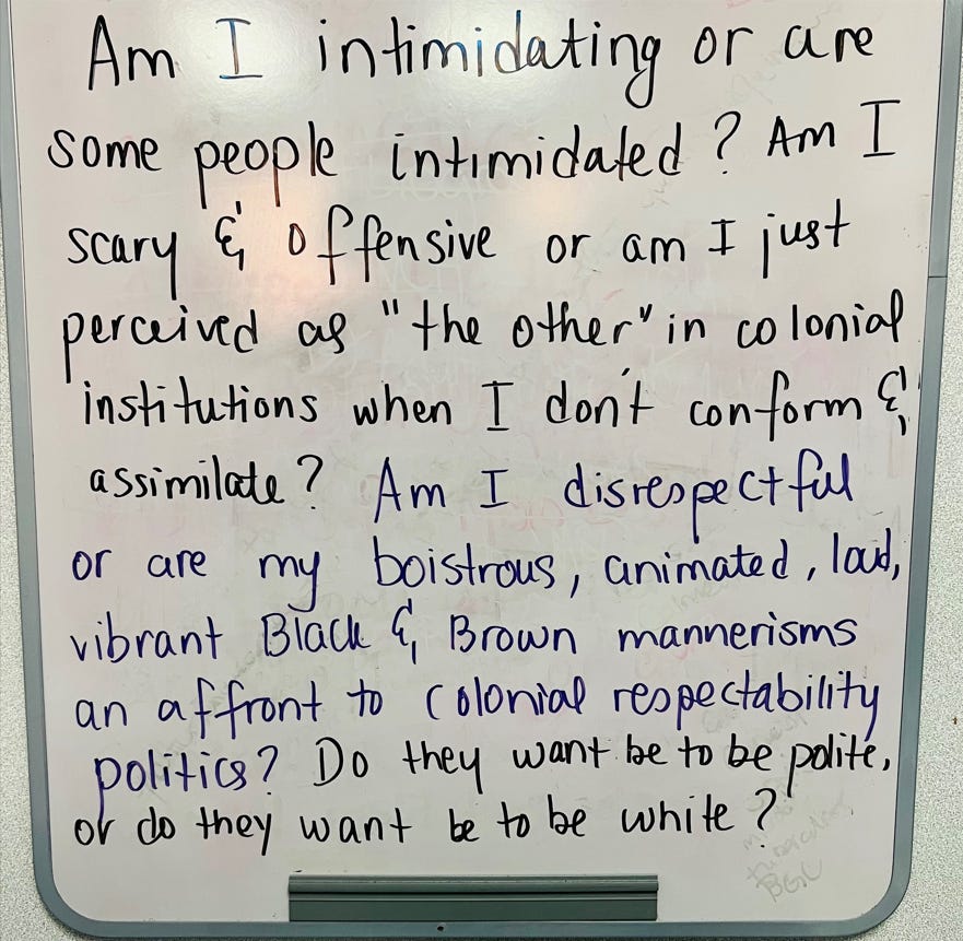 A white board with Ayesha's writing saying "Am I intimidating or are some people intimidated? Am I scary and offensive or am I just perceived as "the other" in colonial institutions when I don't conform & assimilate? Am I disrespectful or are my boisterous, animated, loud, vibrant Black & Brown mannerisms an affront to colonial respectability politics? Do they want me to be polite or do they want me to be white?” 