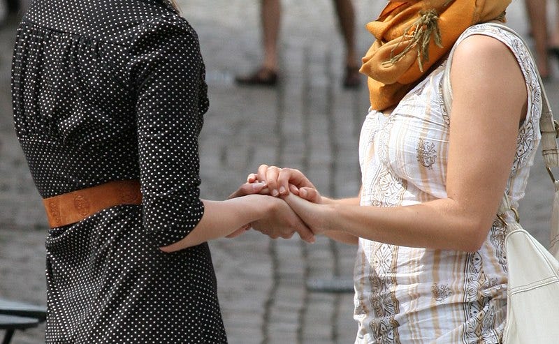 Two women holding hands.