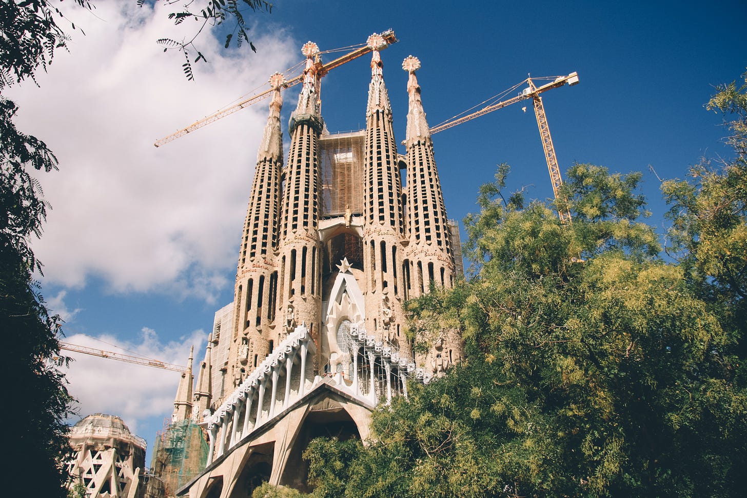 Cranes working above Sagrada Familia, a famous unfinished cathedral in Barcelona, Spain.