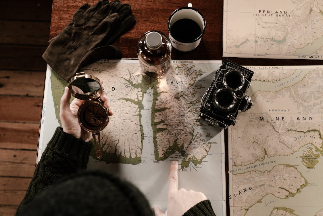 Free Man Looking at a Map and Holding a Vintage Compass Stock Photo