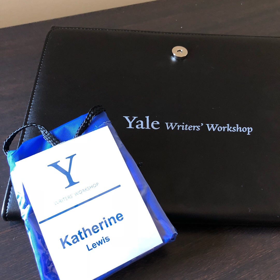 A photo of a black portfolio that says, “Yale Writers’ Workshop.” Kat’s Yale-branded conference lanyard is lying on top of it.
