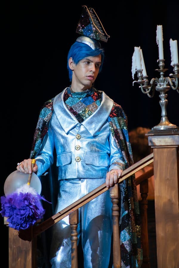 A man standing on a staircase wearing a shiny blue suit and a hat shaped like a staircase.