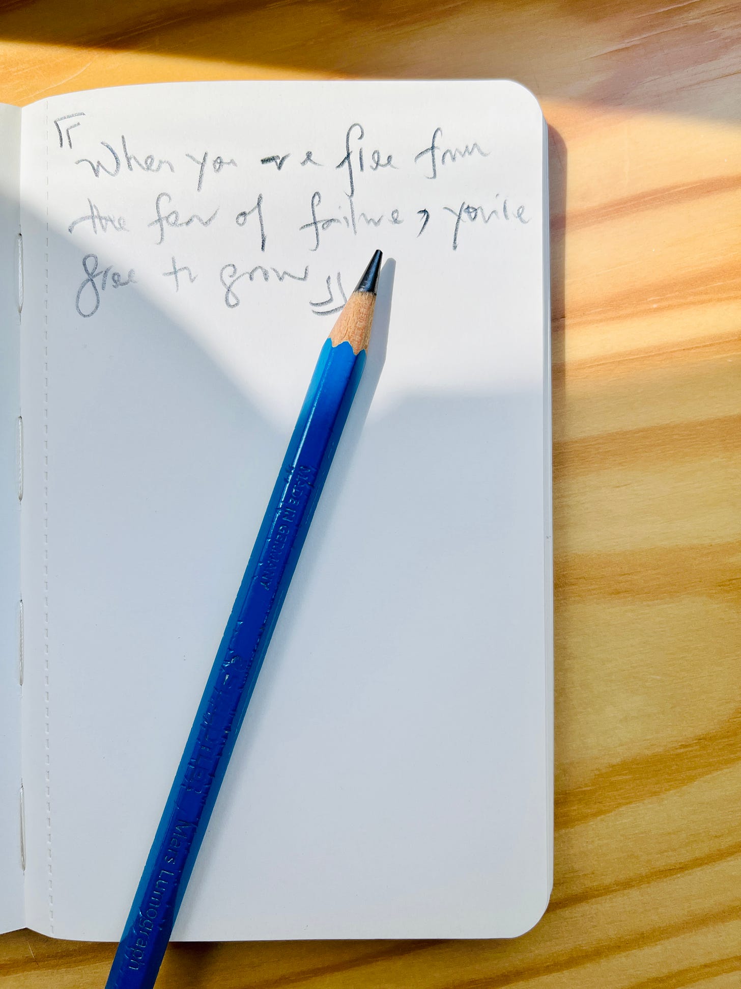 Image: pencil handwritten phrase on a notebook, “When you are free from the fear of failure, you’re free to grow.”