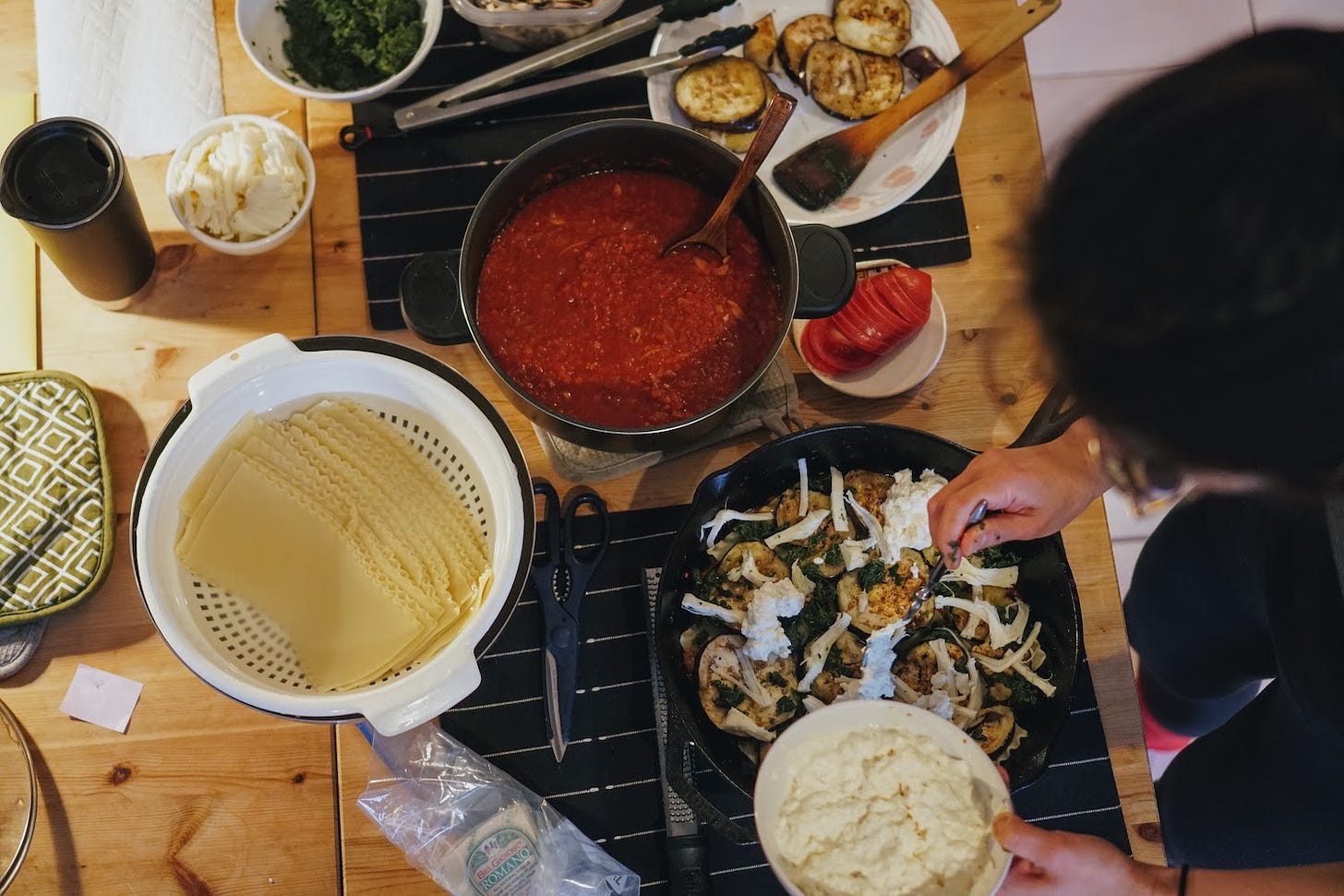 Ingredients for lasagna being assembled in a cast iron