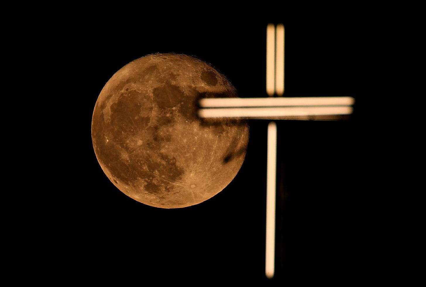 The moon rises over the cross of St. Joseph Church in Baghdad, Iraq, Friday, June 25, 2021. (AP/Photo/Hadi Mizban)