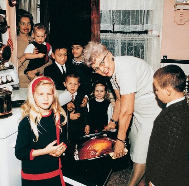 Uma senhora tirando um peru de Natal do forno rodeada por crianças