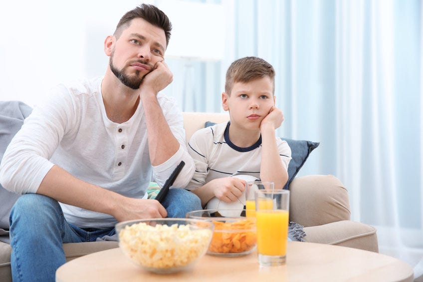 Father and son watching football on television.