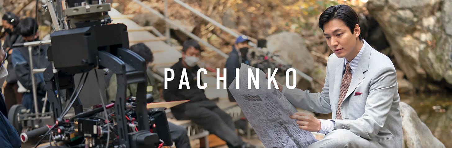 Behind the scenes filming Pachinko tv series. Man is reading a newspaper while camera gear is in view.