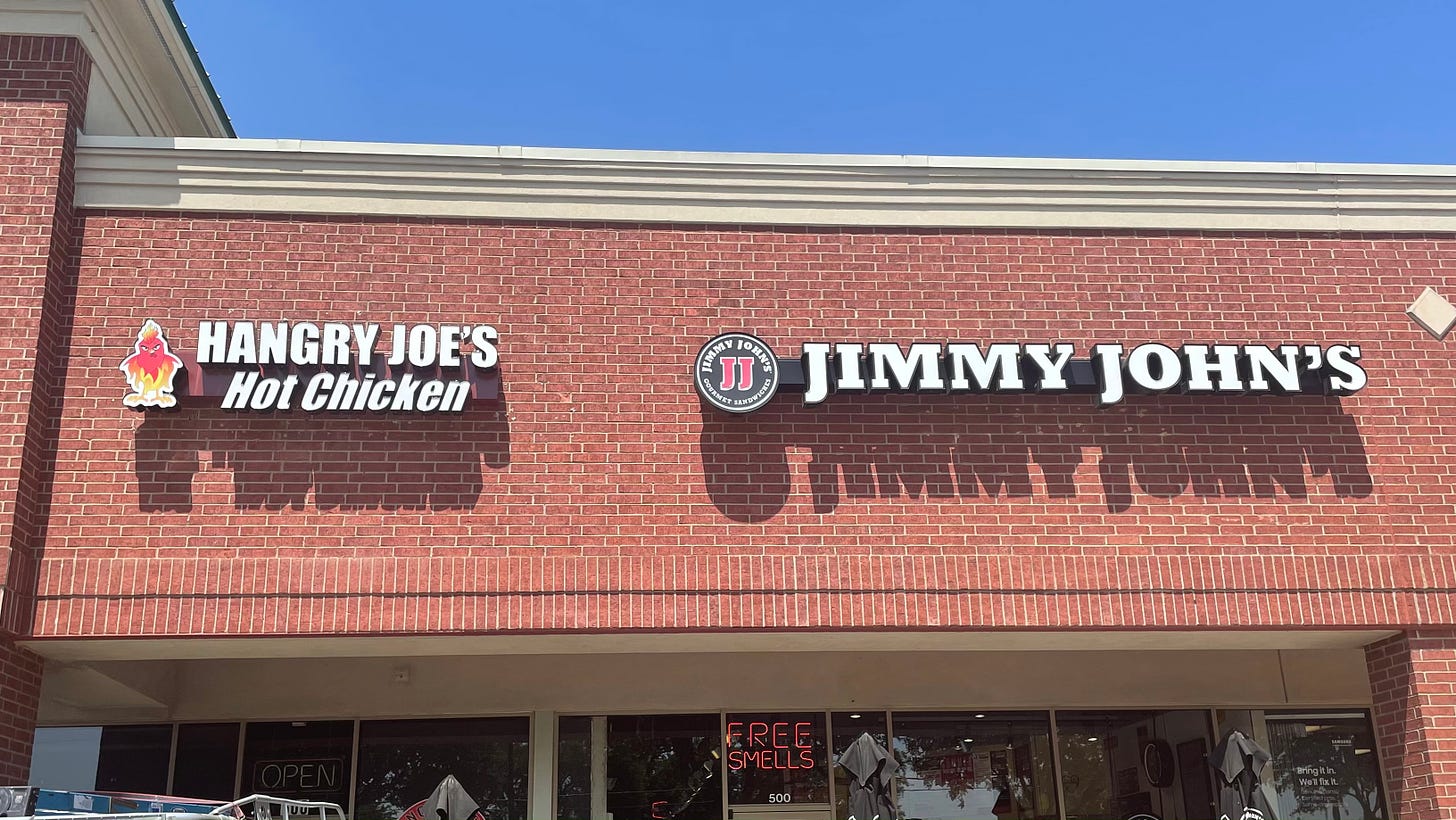 Side-by-side signs for restaurants called Hangry Joe's Hot Chicken and Jimmy John's
