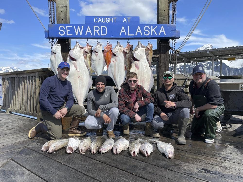 Captain John Moline, right, poses for a photo with others during the annual ASYMCA Alaska Combat Fishing Tournament on May 25, 2022, in Seward, Alaska. The tournament, which began in 2007 and now involves more than 300 soldiers, includes a day of deep-water fishing followed by a celebratory banquet with prizes for the largest catch, smallest catch and soldier who got the sickest. (Armed Services YMCA via AP)