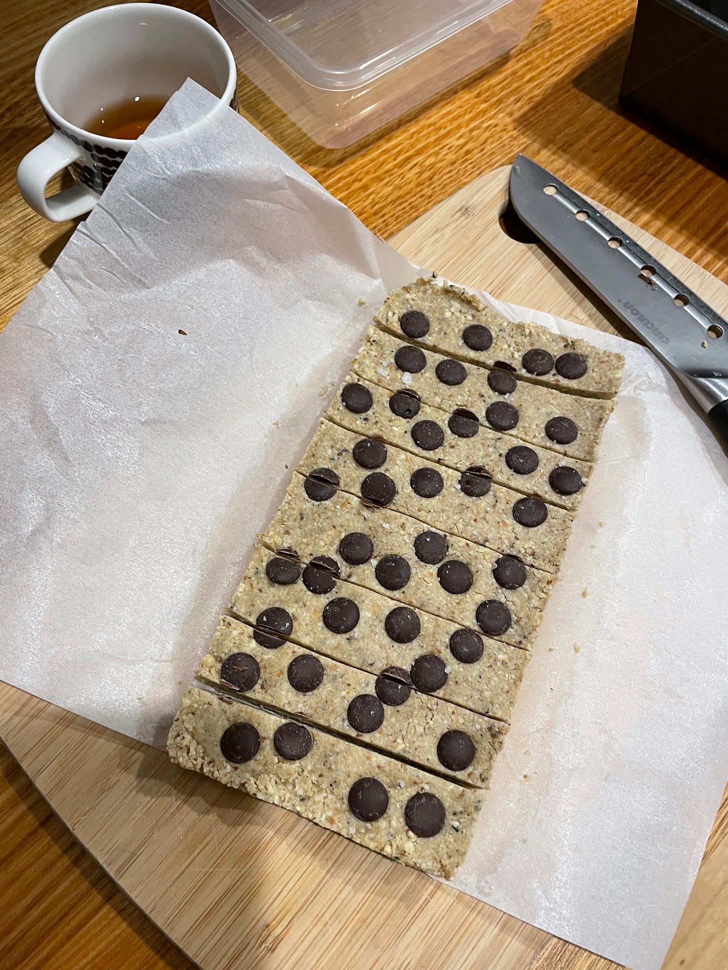 A slab of cookie dough oat bars, sliced into eight pieces. A peppermint tea nearby.