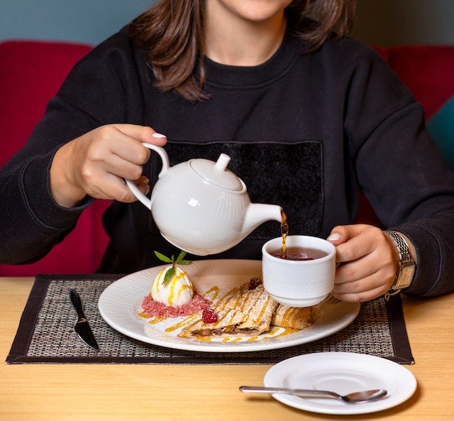 Woman pouring tea with dessert at a restaurant