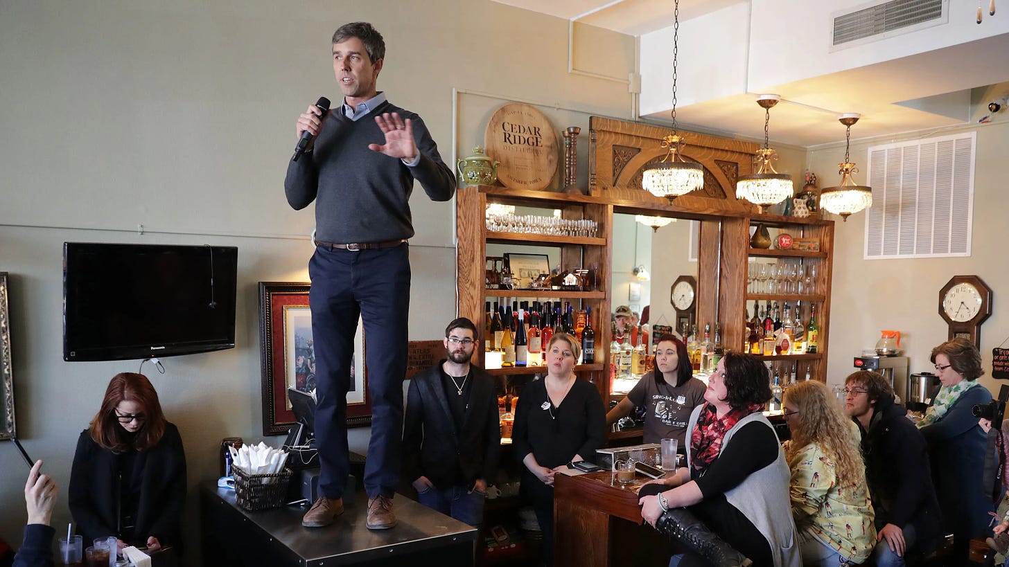 Robert "Beto" O'Rourke stands on a table to address supporters.