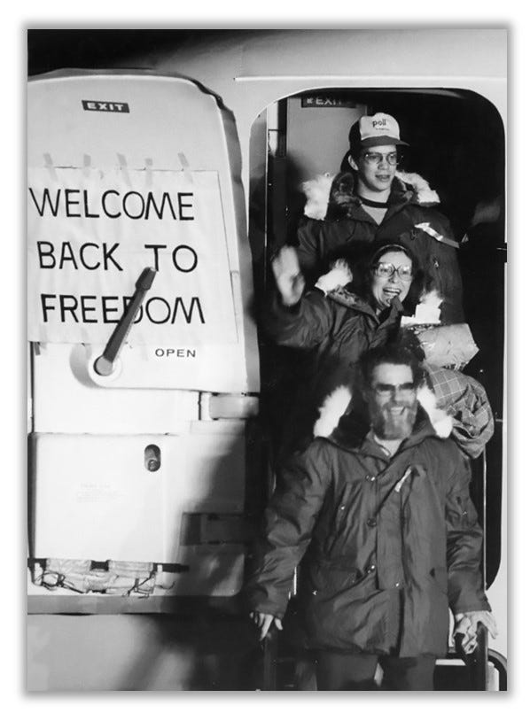 Hostages depart a plane in Germany. They have huge smiles on their faces.  A sign on the plane door says "Welcome back to freedom"! 