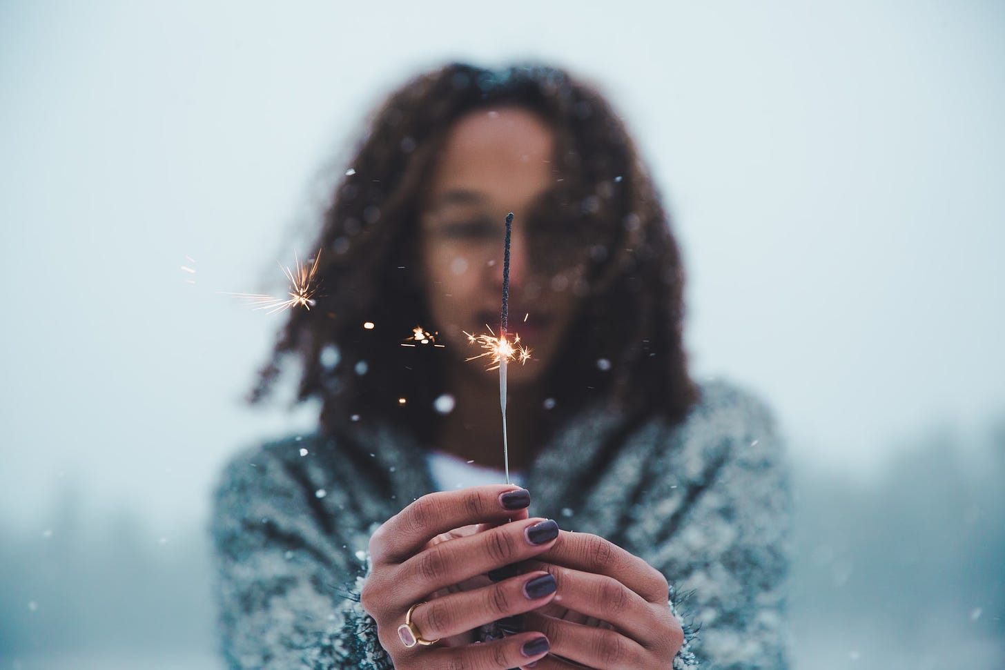 a women holding a half used sparkler in the snow