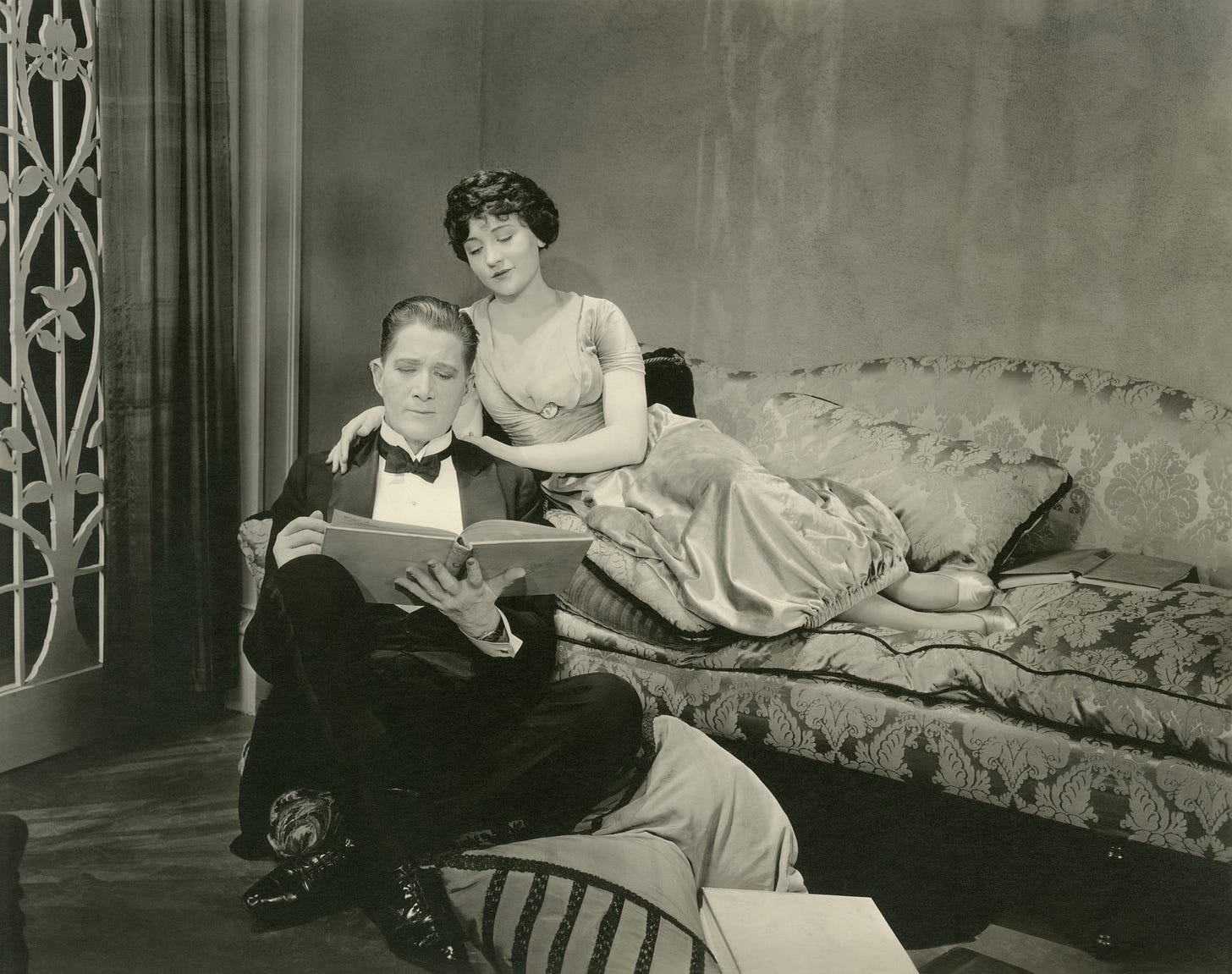 Happy vintage couple reading together, perhaps a bit overdressed. 
