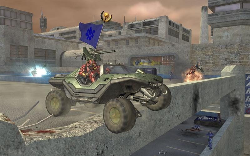 A Warthog jumps off the side of a crumbling building, a flag carrying Spartan in the passenger seat.