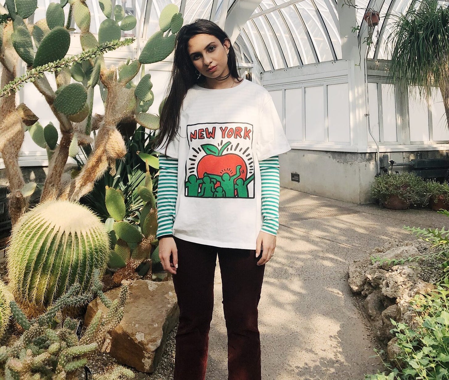 Portrait of Zaria Parvez standing in a cactus garden wearing a shirt that says "New York"
