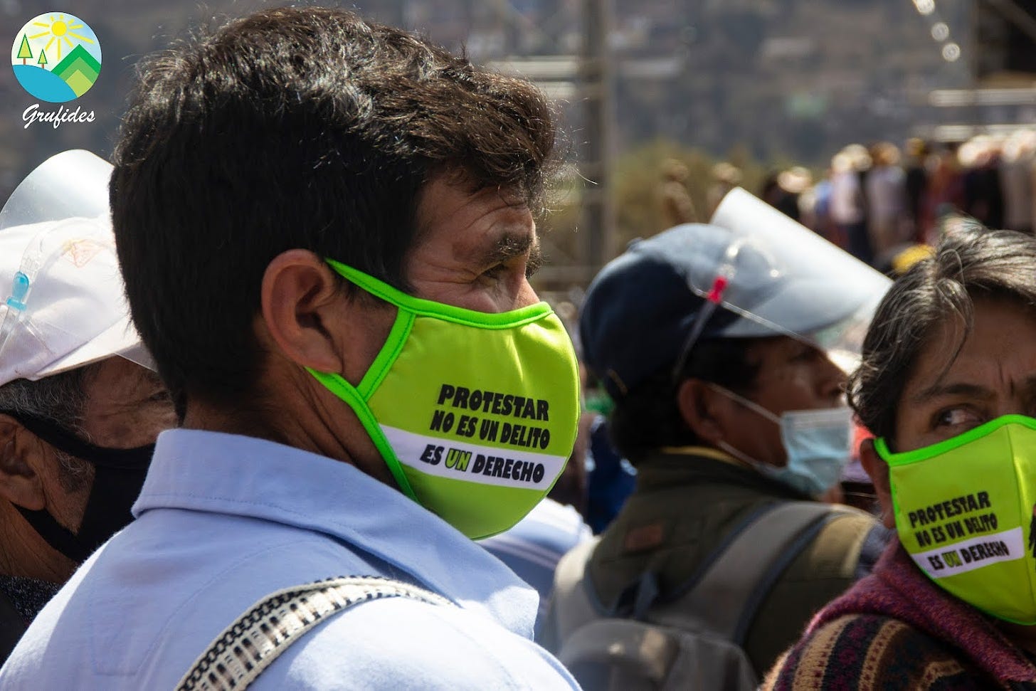Rosas, a middle-aged Peruvian man with short black hair and a white shirt, joins a protest wearing a yellow facemask that says 'Protestar no es un delito es un derecho'