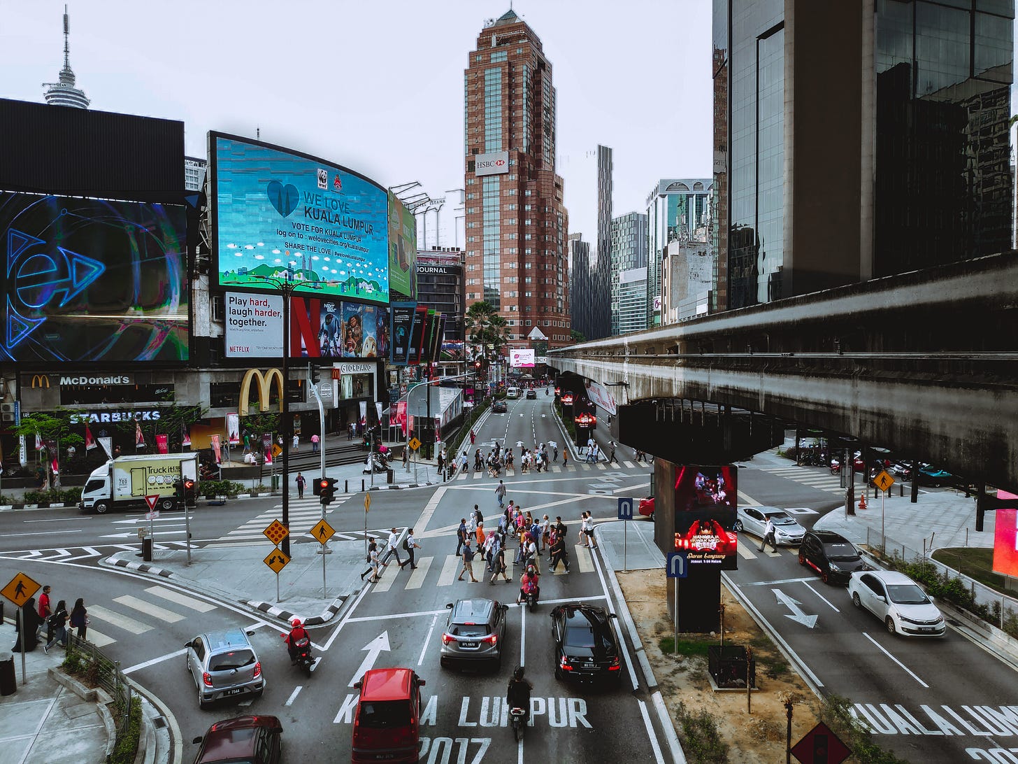 Free From above of modern metropolis with multistage buildings and asphalt roadway with marking lines and driving automobiles near group of unrecognizable pedestrians crossing road in daylight Stock Photo