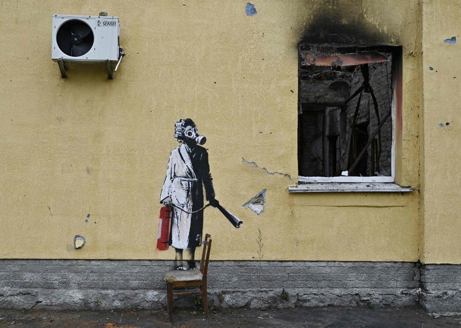 A painting on the wall of a burned-out building depicts a person wearing a gas mask and holding a fire extinguisher.