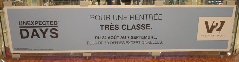 Banner in shopping mall with slogan in English: “Unexpected Days.” Then, in French: “Pour une rentrée très classe.”