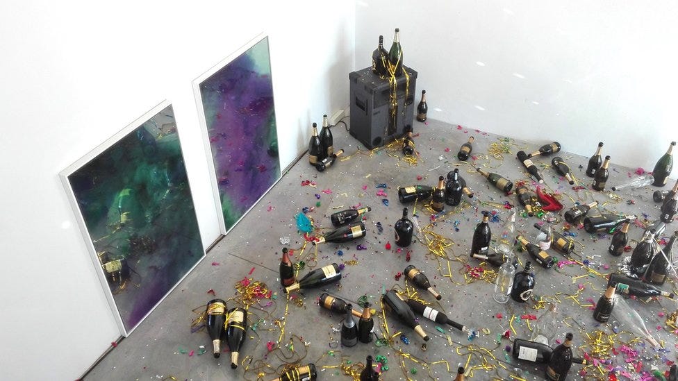 The artwork consists of empty champagne bottles, confetti and cigarette butts