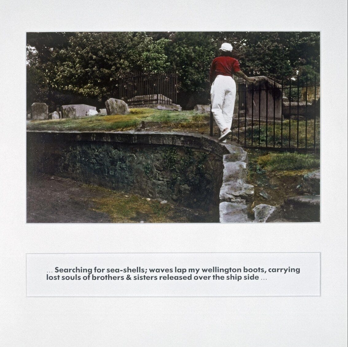 Photo from Ingrid Pollard's collection "pastoral interlude" of a Black British woman walking in front of a peaceful green cemetery.