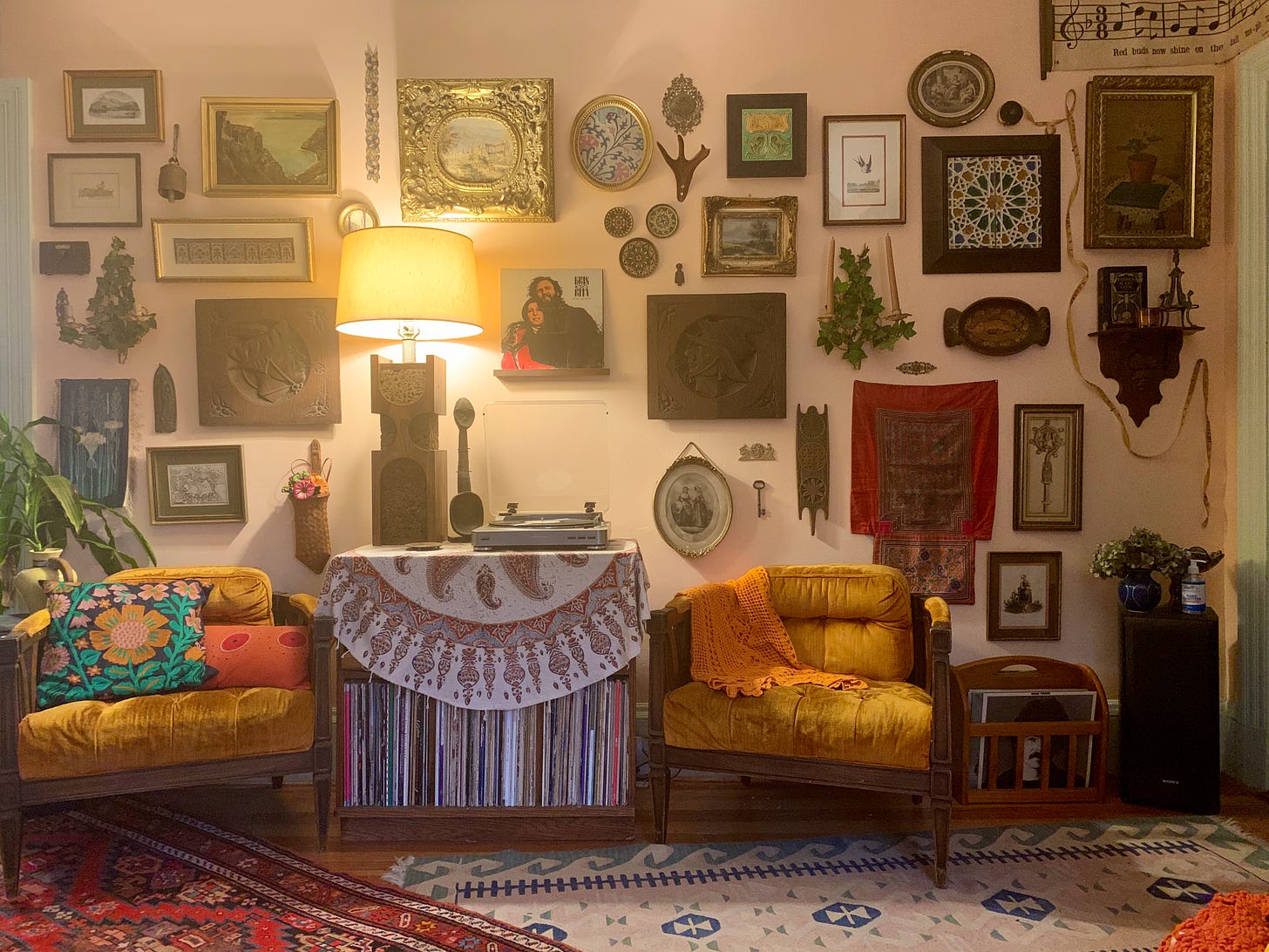a living room wall with a very large number of pictures, sconces, and objects hanging on it