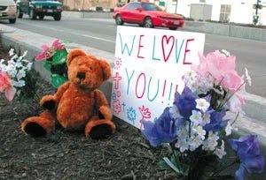 Artificial flowers and a $7.99 teddy bear adorn the site of the tragedy.