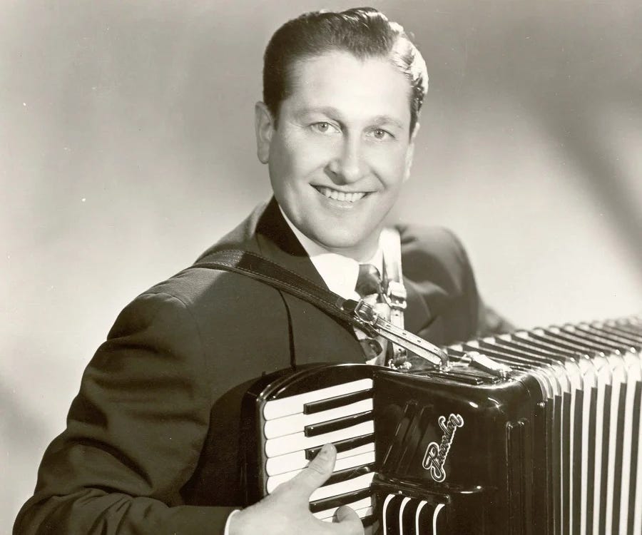 an image of Lawrence Welk, smiling, holding/wearing an accordion as if about to play