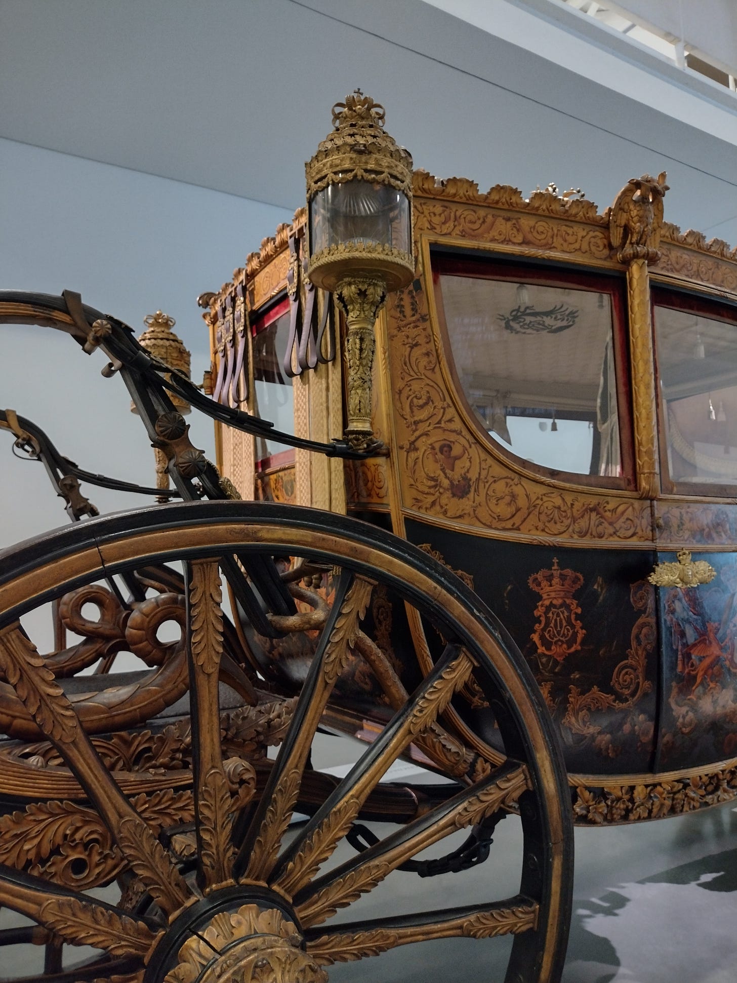 Image of the wheel and carriage of an ornate coach.
