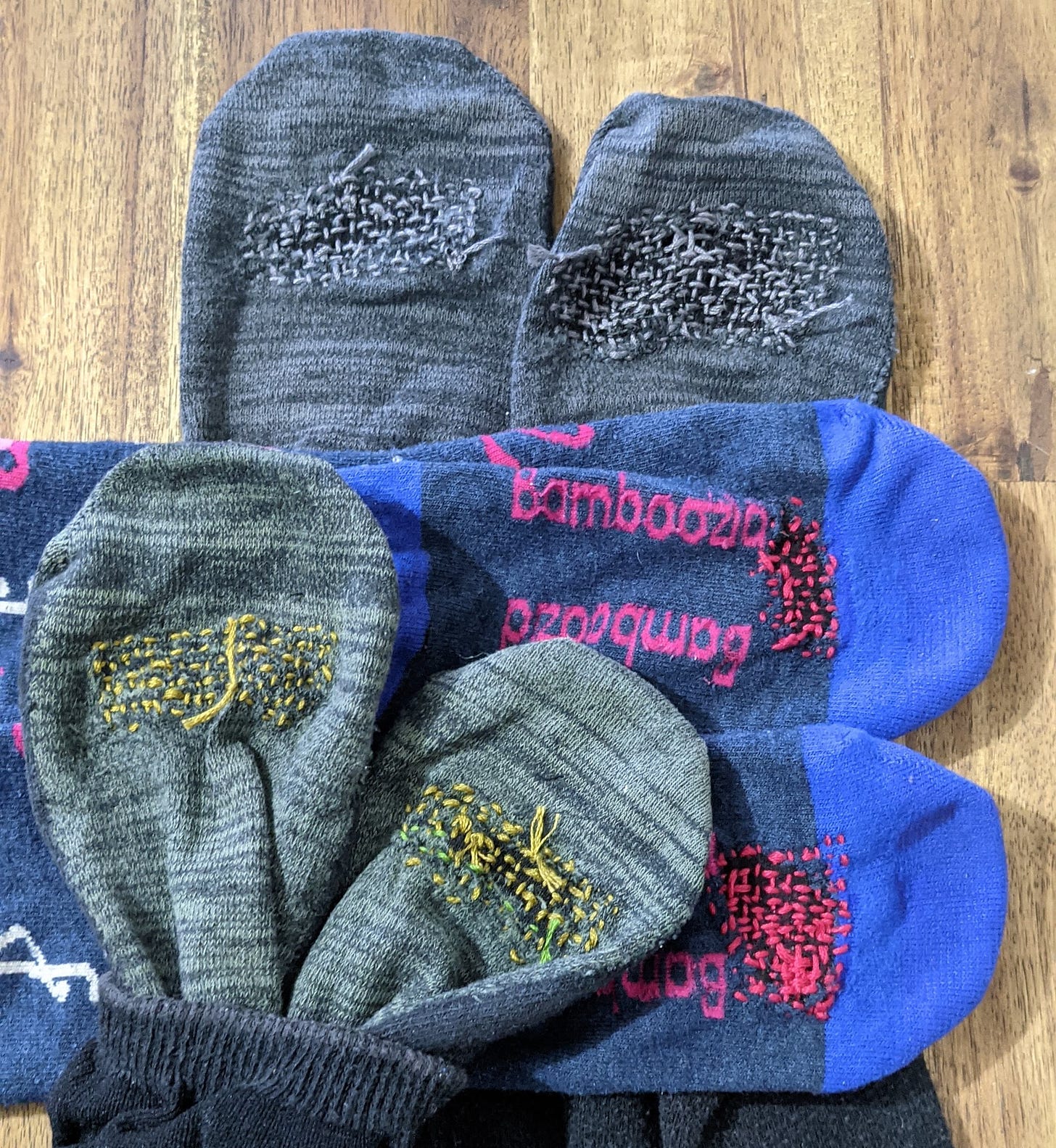 A pile of colourful socks with visible mending on the bottom