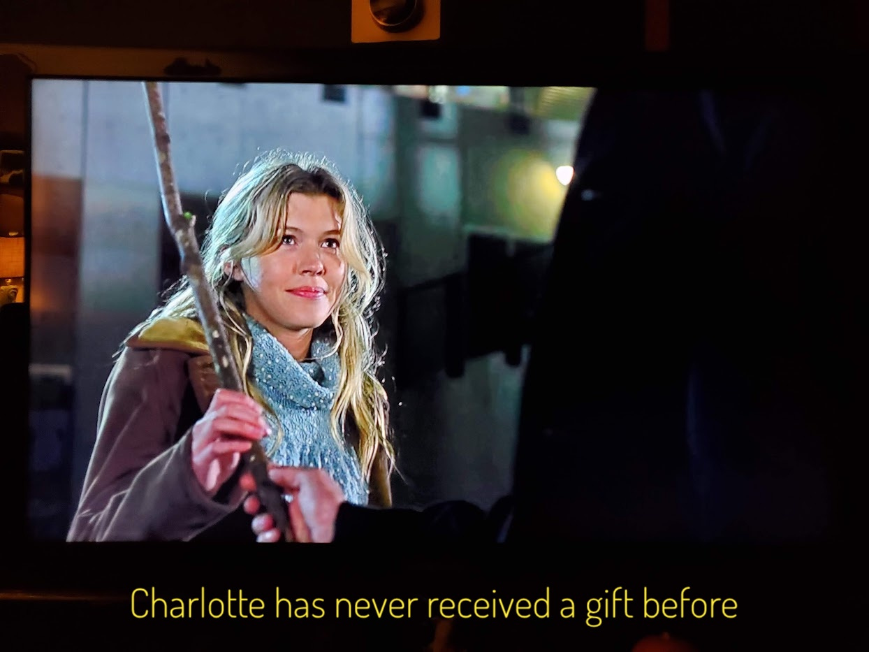 Charlotte, a blonde woman, receiving a large stick, captioned "Charlotte has never received a gift before"
