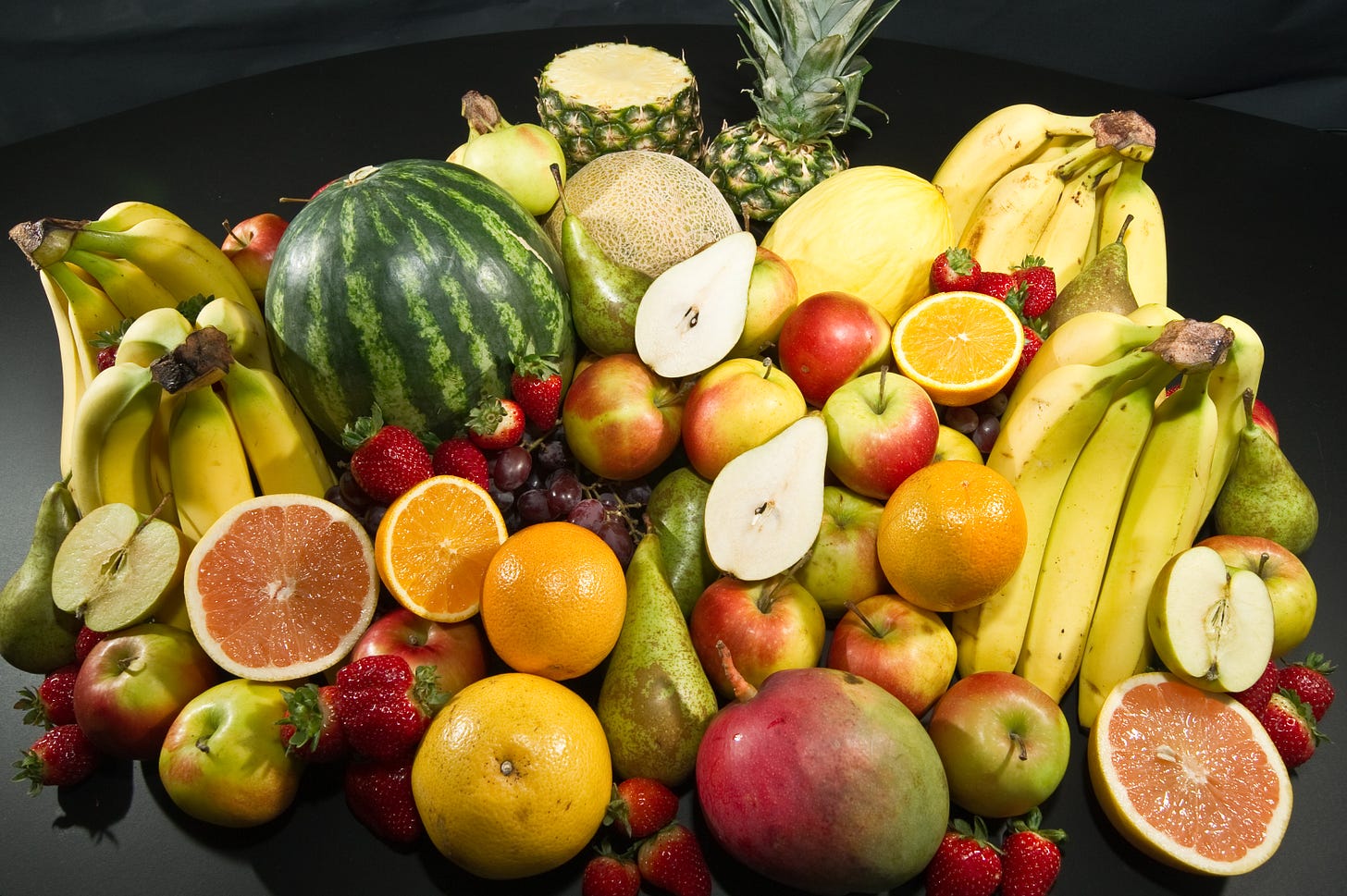 A collection of a lot of different kinds of fruit, including a watermellon, apples, bananas and strawberries