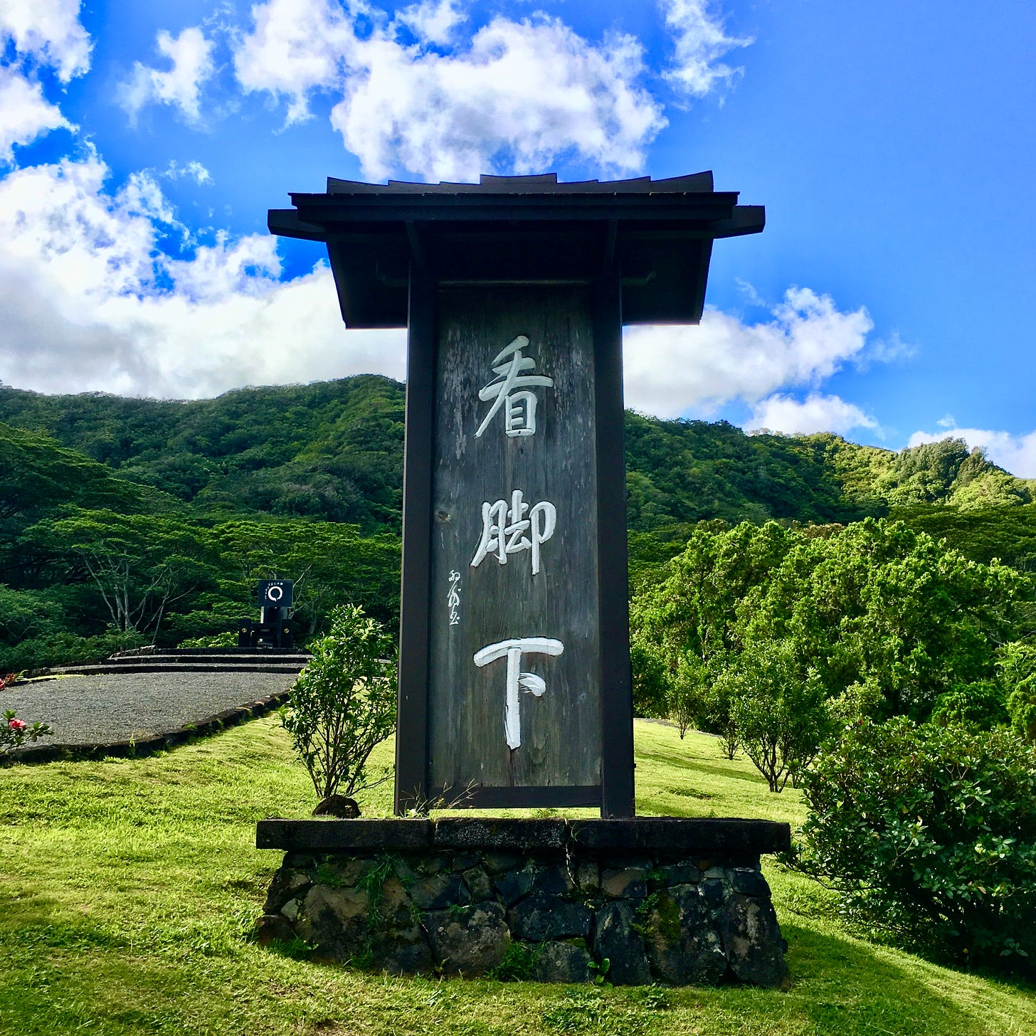 A wooden sign with Chinese characters on a grassy hill