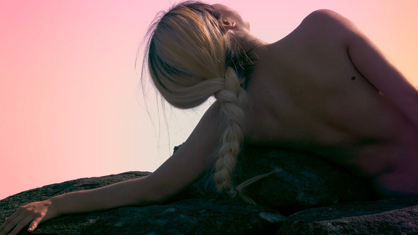 A nude modern dancer with silvery braided hair leans against a stone during a dance sequence in “Yeh Shih-tao: A Taiwan Man”
