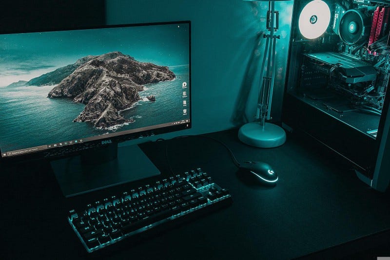 A windows gaming setup with blue/green lighting and macOS wallpaper on monitor