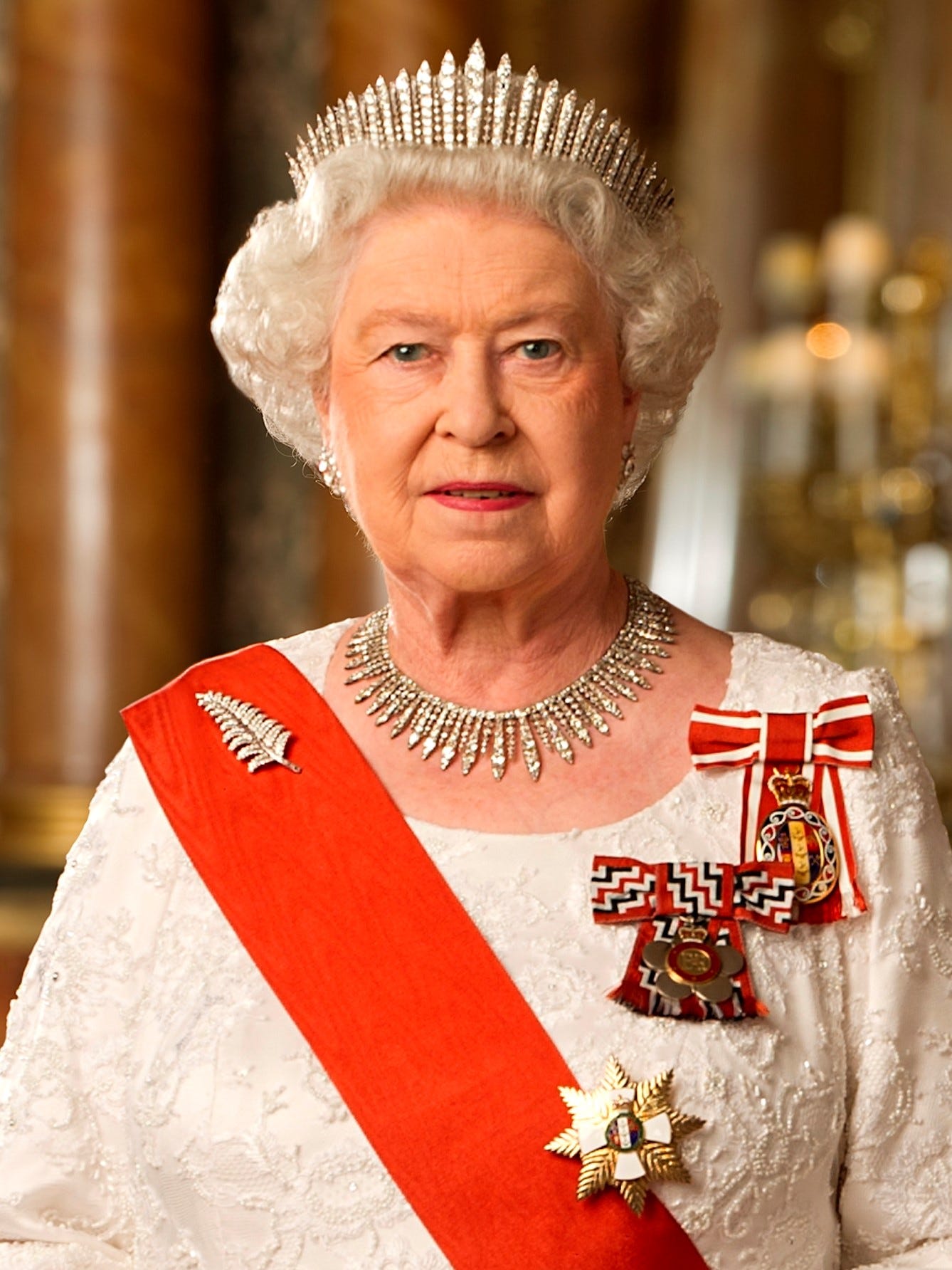 Her Majesty Queen Elizabeth II, Queen of New Zealand, in the Blue Room of Buckingham Palace. She is wearing: a diamond fern brooch given to her in 1953 by the women of Auckland, Queen Mary's Fringe Tiara, the City of London Fringe Necklace, the insignia of the Sovereign of the Order of New Zealand, the badge of the Queen's Service Order, and the sash and star of the New Zealand Order of Merit. One of Queen Mary's Chain-Link Bracelets is on her right wrist. Official portrait taken in 2011 and released on 7 February 2012 to mark the Queen's Diamond Jubilee.