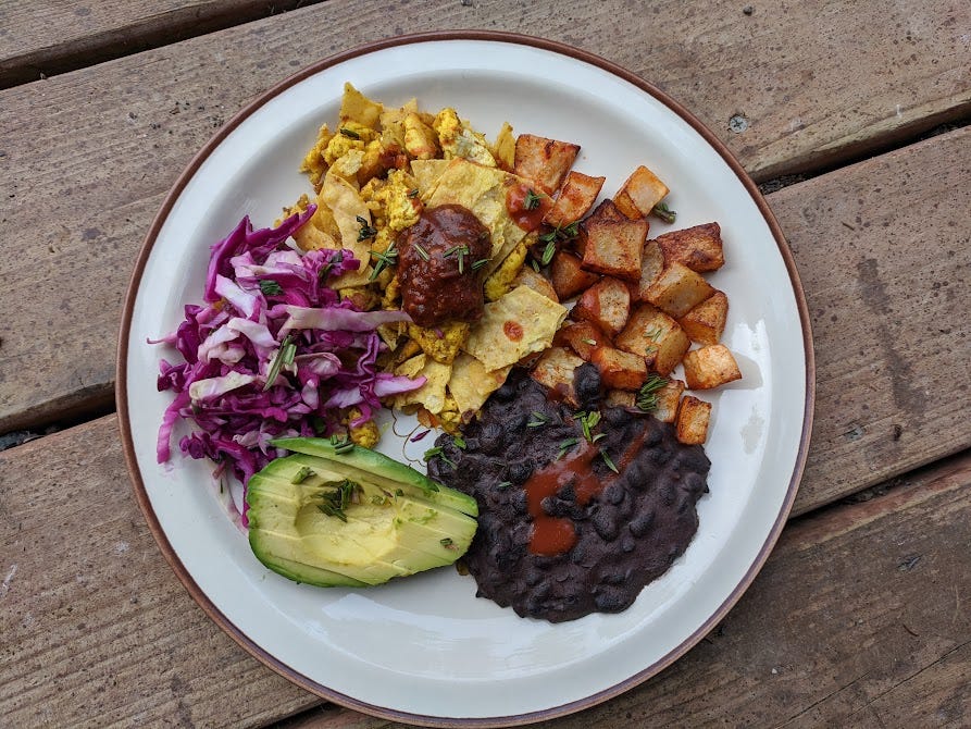 a plate of tofu migas, chipotle salsa, black beans, avocado and cabbage slaw with minced fireweed leaves on top a plate of tofu migas, chipotle salsa, black beans, avocado and cabbage slaw with minced fireweed leaves on top
