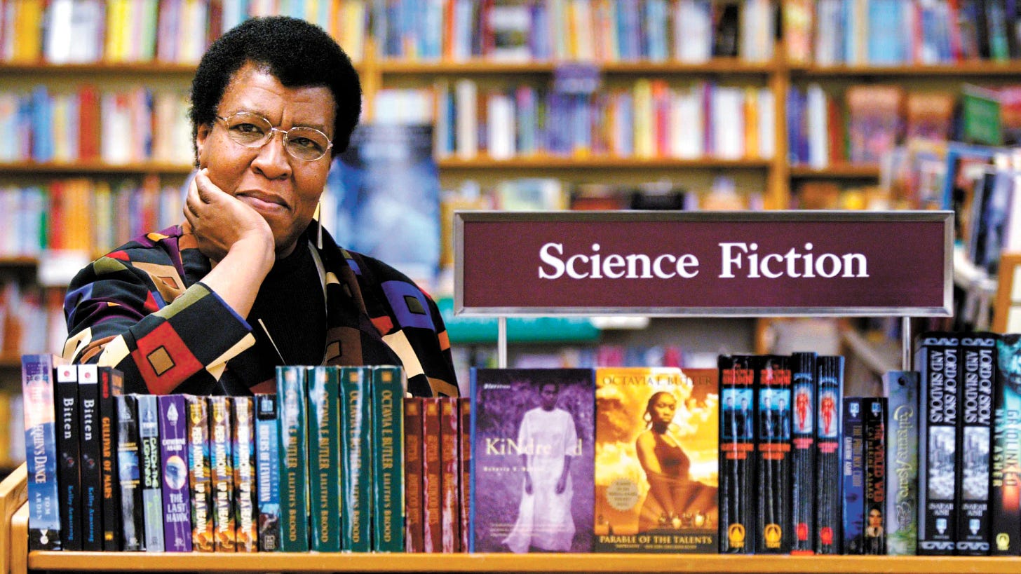 This photo shows author Octavia E. Butler sitting with some of her novels at a book signing held in Seattle, Washington on 4 February 2004. A placard bearing the words "Science Fiction" is attached to the table at which Butler sits.