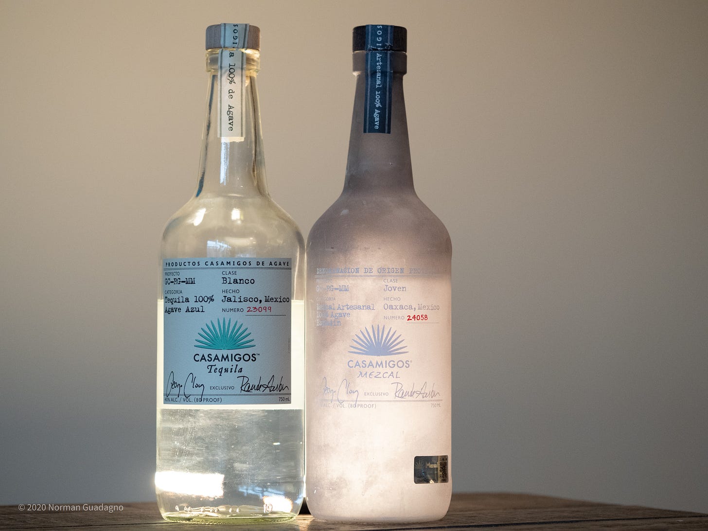 photo of two bottles backlit, a clear tequila bottle and a frosted mezcal bottle