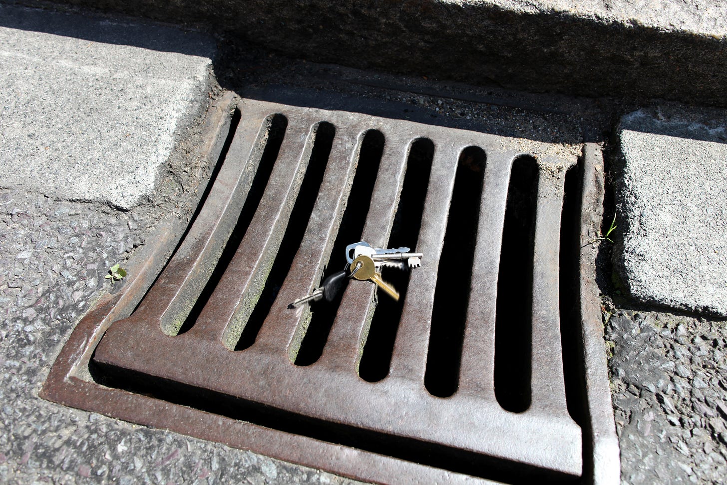A set of keys resting precariously on a sewer grate