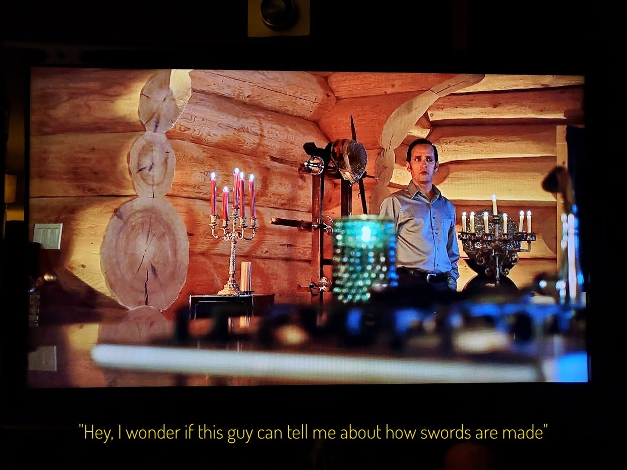 Duncan alone in Cole's house, surrounded by lit candelabras and weapons, captioned "Hey I wonder if this guy can tell me about how swords are made"