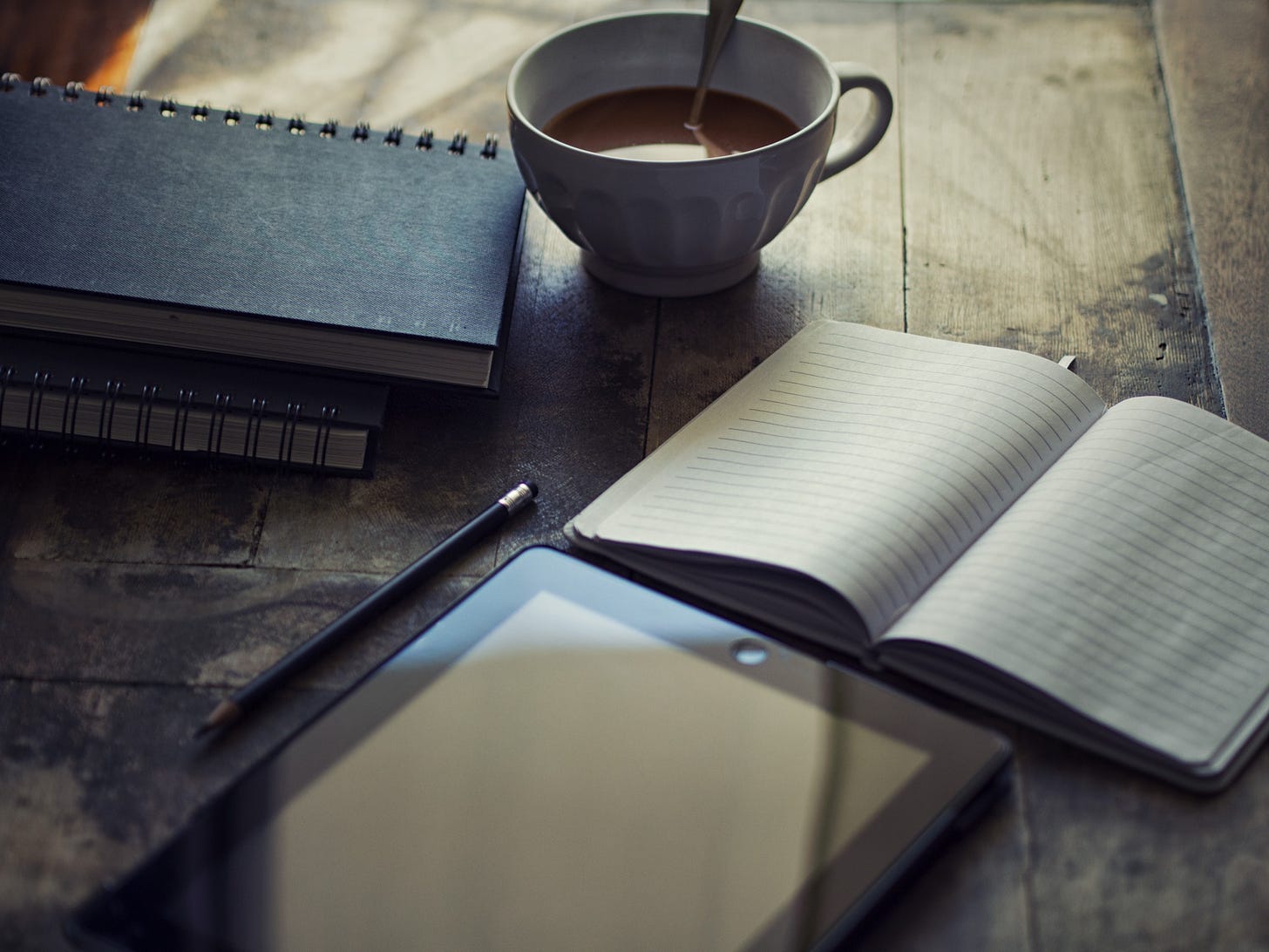 Image of a coffee cup, writing pad and tablet on a table for article by Larry G. Maguire