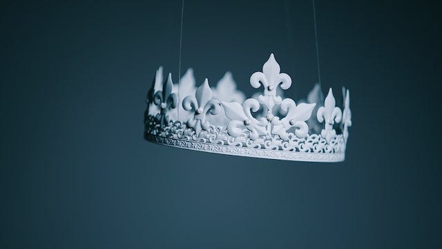 An ornate white crown, suspended in mid-air by very fine strings, against a blue-gray background.