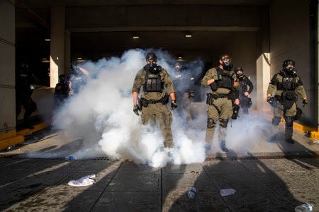 Police in riot gear deploy tear gas and pepper spray against protesters inside the Wake County Public Safety Center parking deck, Saturday, May 30, 2020, in Raleigh, N.C., as people nationwide protested the Memorial Day death of George Floyd, who died in police custody in Minneapolis. (Travis Long/The News & Observer via AP)