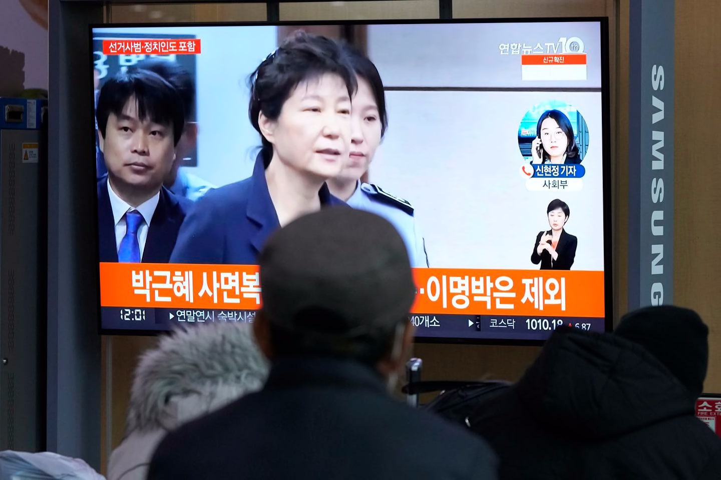 People watched a TV screen showing a file image of former South Korean president Park Geun-hye during a news program at the Seoul Railway Station on Friday. The South Korean government said it will grant a special pardon to Park, who is serving a lengthy prison term for bribery and other crimes.