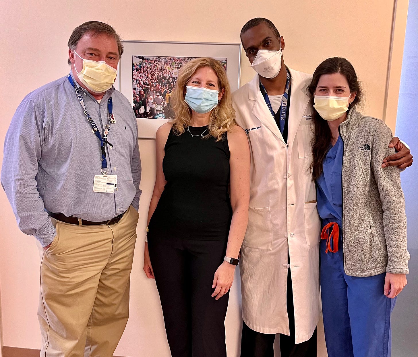 Four people standing in hallway, nurse, doctors and patient