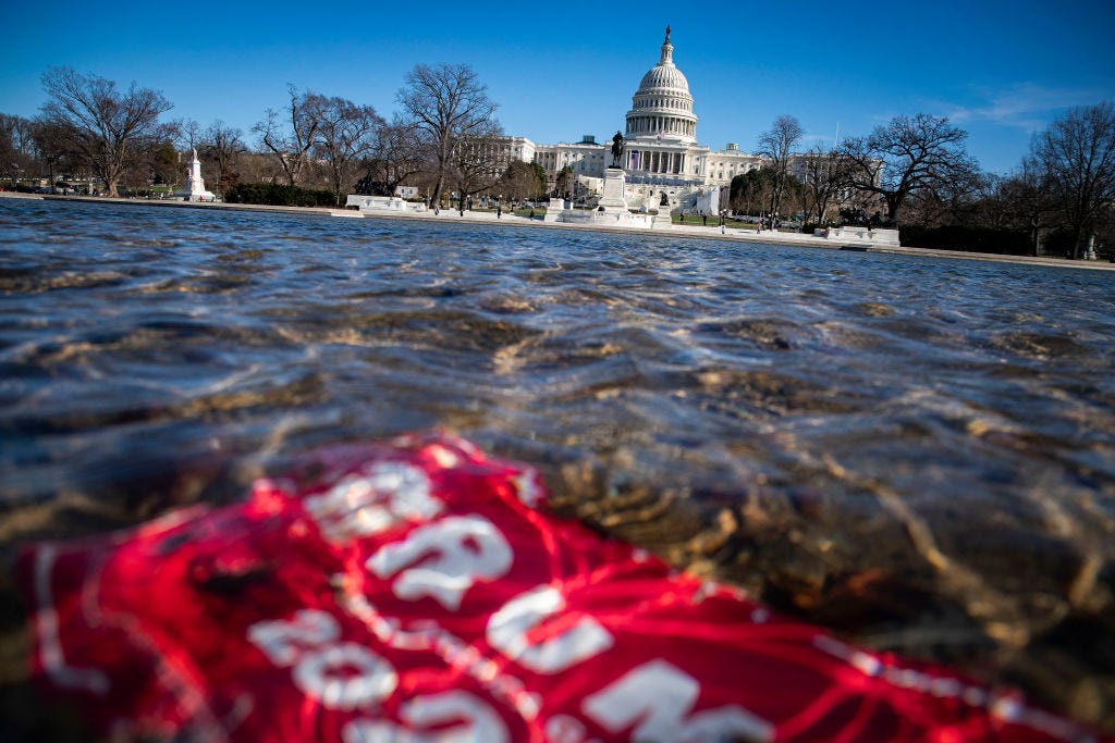 A campaign sign for PresidentTrump lies beneath water in the Capitol Reflecting Pool on Saturday in Washington, DC. (Al Drago/Getty Images)